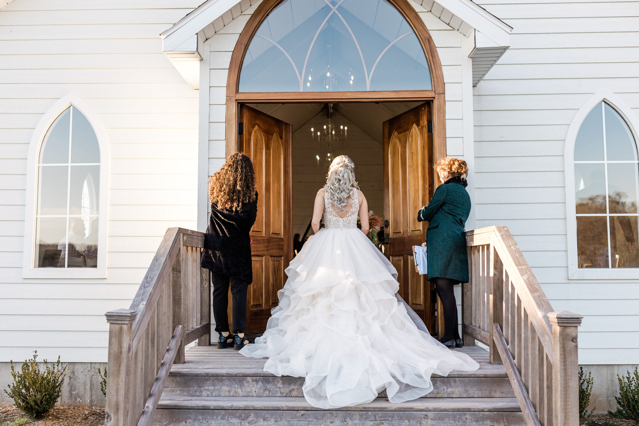 Bride enters white wedding chapel.